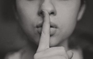 Girl making be quiet symbol with finger over mouth