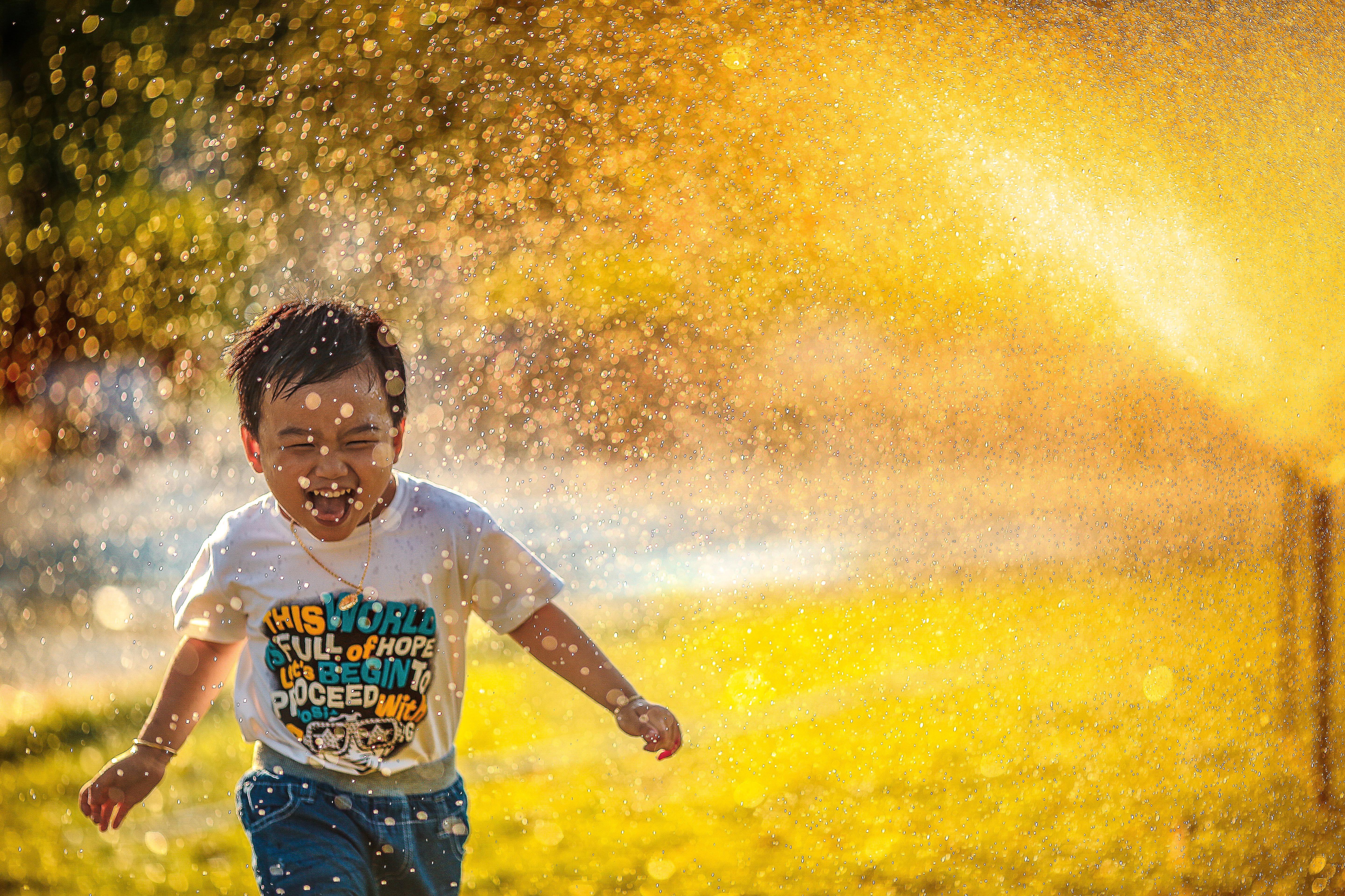 Happy kid running in sprinklers