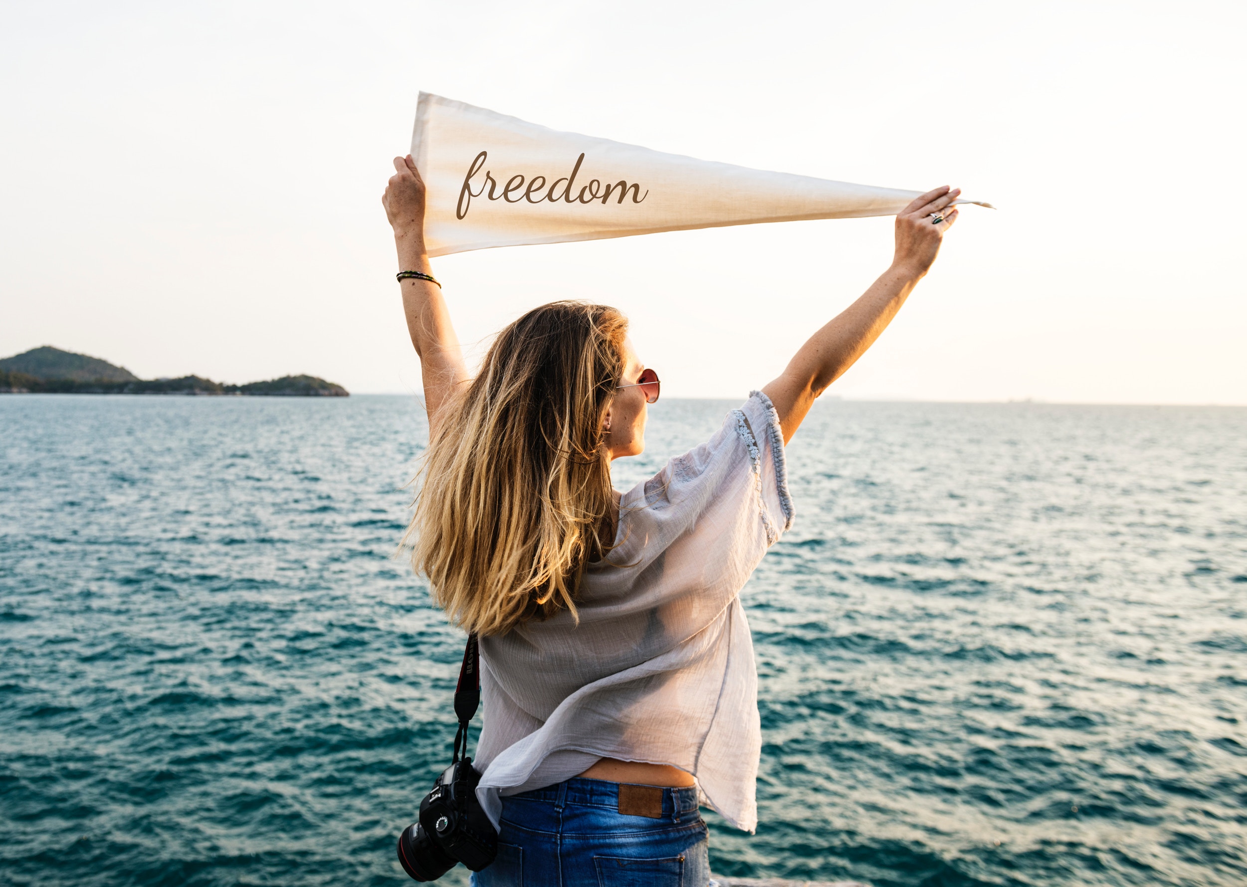 Woman holding freedom sign in front of ocean